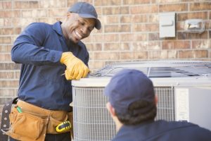 smiling-HVAC-technician-performing-maintenance-on-an-air-conditioner